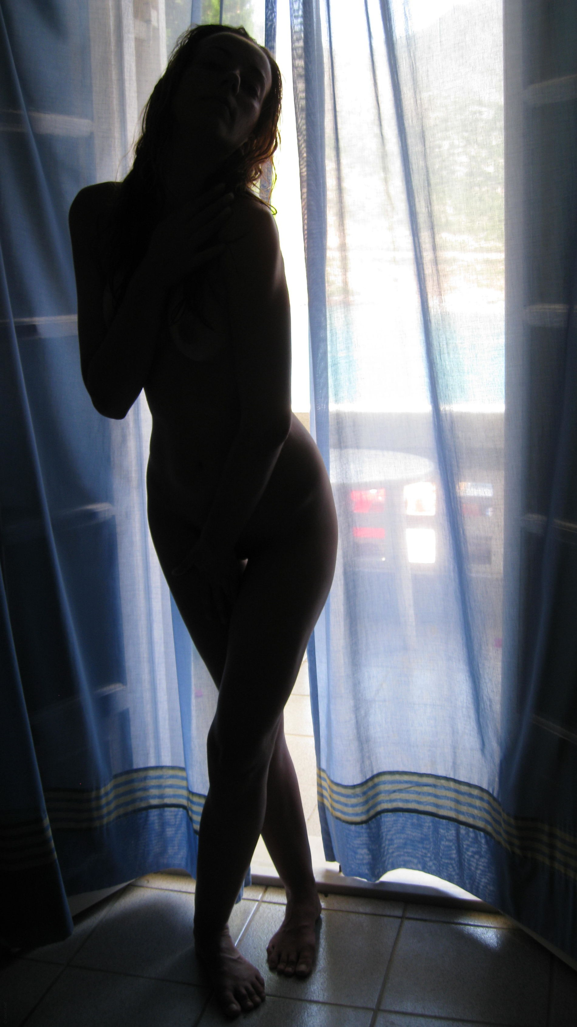 Nude girl posing by hotel room window for explicit photoshoot