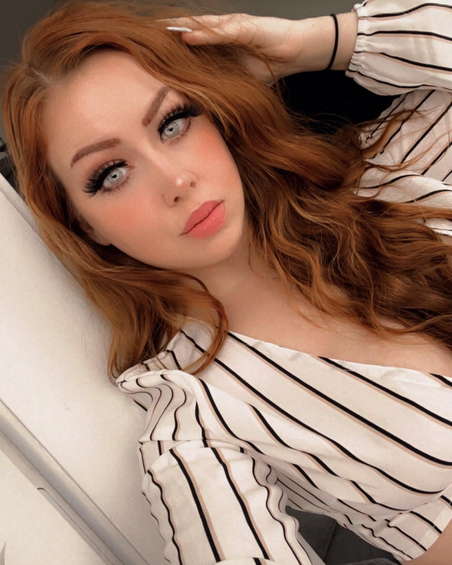 Redhead girl flaunts smooth-shaven intimate area and alluring breasts in selfie.