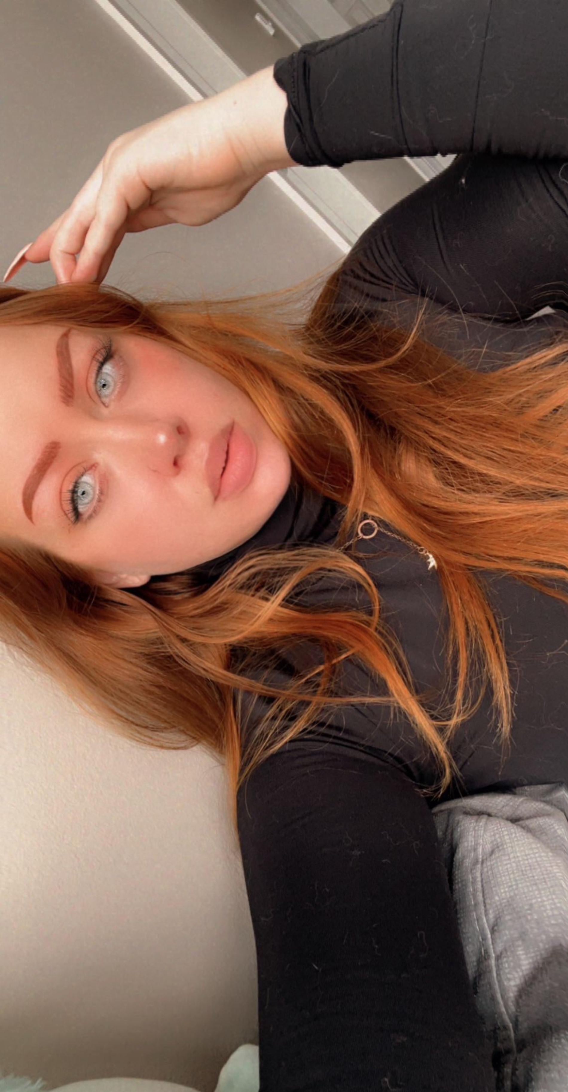 Redhead girl flaunts smooth-shaven intimate area and alluring breasts in selfie.